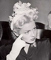 Woman wearing flowered hairpiece looking into camera