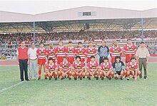 Team photo at a stadium, in front of fans in the stands