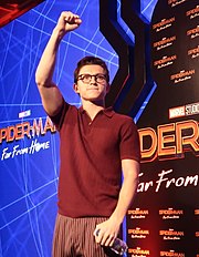 Tom Holland looking to his right while raising his left hand and holding his fist