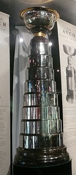 Tall and slender silver trophy with a silver bowl mounted above eight rings engraved with names of players