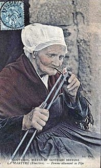 An old photograph of a La Martyre woman smoking a pipe.