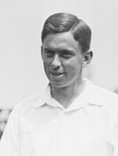 A black-haired man in a white shirt poses for the picture