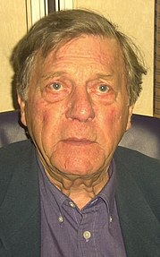 A 75-year-old man with a straight face looking into the camera.