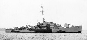 A warship facing right in dazzle camouflage