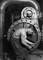 Image 35Lewis Hine's 1920 image "Power house mechanic working on steam pump," which shows a working class young American man with wrench in hand, hunched over, surrounded by the machinery that defines his work.