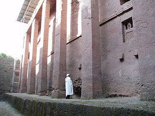 Man standing beside the walls of Biete Medhane Alem, believed to be the largest monolithic church in the world