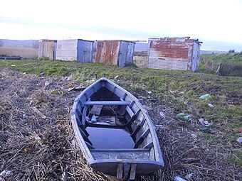A gandelow used by the fishermen of Coonagh, with fishermens' cabins in the background