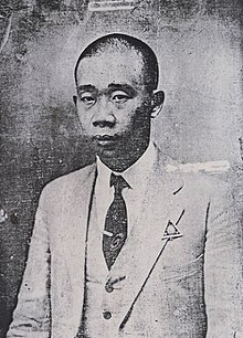 A black and white photo of Zhou Xicheng, wearing a suit