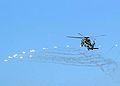 An SH-60B deploys its flares while evasively maneuvering