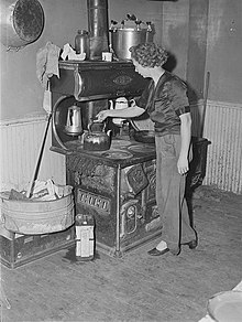 Metal can of motor oil next to wood burning stove and oven; used for getting the wood burning; 1940