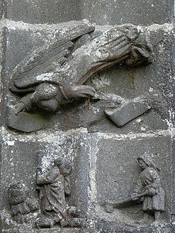 Carving on south porch arch. An angel appears to be diving towards the ground. She holds a phylactery. There are two carvings beneath her. That on the right shows a farmer at work.