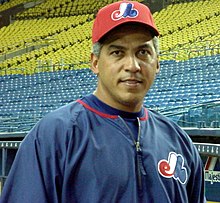 A baseball player wearing a blue jacket and red cap