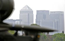 Photograph of a missile system in the foreground and the Canary Wharf skyline in the background.