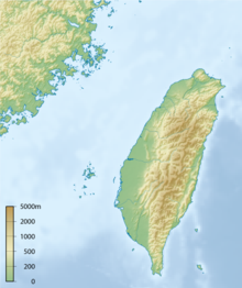 A topographical map of Taiwan, showing altitude with colours; green lowlands along the island's western edge with a spine of mountains down the center and east showing in various shades of brown