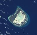 Astove Atoll, slightly oblique view from space. Note the wide land area (dark) surrounding the whitish lagoon