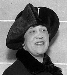 A head-and-shoulders photo of a Caucasian woman facing slightly right, wearing a dark coat with fur trim, and a hat