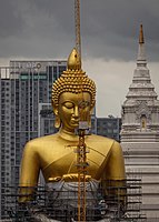 Buddha image covered with scaffolding and with a crane next to it.