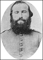 Black and white photo shows a bearded man in a plain gray uniform.