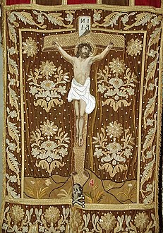 A processional banner in the Sainte-Nonne church depicting Christ's crucifixion. Note the "Ankou" at the base of the cross.