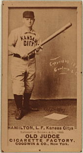A baseball player is standing, holding a baseball bat.