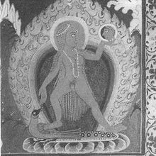 A nude woman with long hair and wearing a pearl necklace and headband, stands on a peacock (which in turn sits on a lotus) with her legs apart. She holds a mirror in her left hand and looks at her reflection in it. An aureole and halo surround her.