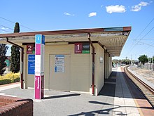 Asphalt station platform with a small brick shelter building
