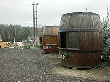 Several stalls shaped like barrels on a gravel field