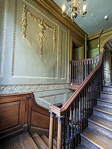 A staircase with mahogany railings and restored decorative paintwork