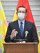 Oscar Ortiz delivers a press conference while wearing a surgical mask.