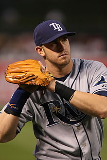 A man in a gray baseball jersey and navy blue cap