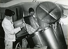 Sailors load a cooking vat with food