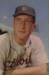 A man in a navy blue baseball cap and a grey baseball uniform shown from the chest up looks to his right.