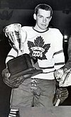 Howie Meeker in Toronto Maple Leafs uniform holding a trophy in his right hand in a black and white photograph