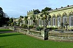 a stone terrace with pools and flower beds in front of a stone-built orangery