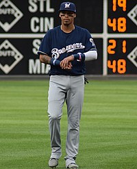 A man wearing a navy blue baseball jersey and cap with gray pants