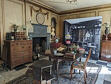 A room with an elaborate 18th century fireplace and an array of 19th century furniture and decorative objects
