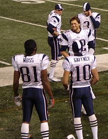 Several Patriots standing at the sideline