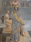 Ancient Greek statue of a lady with blue and gilt garment, a fan and a sun hat, from Tanagra, c. 325–300 BC.
