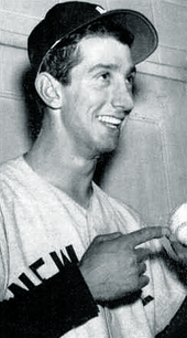 A candid shot of a young man in a baseball uniform, smiling and holding a baseball
