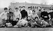 Group photograph of football players wearing 1900s-era uniforms, some kneeling and others laying on the ground