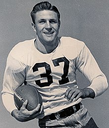 Doak Walker carrying a football and smiling while wearing a shirt with the number 37 on it.