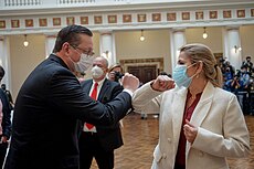 Jeanine Áñez and Oscar Ortiz bump elbows while wearing surgical masks.