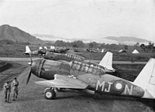 Black and white photo of a large number of single-engined military monoplanes at an airfield with mountains in the background