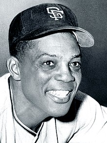 Black-and-white photo of Willie Mays, smiling in a San Francisco Giants hat