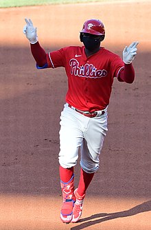 Phillies shortstop Didi Gregorius, wearing a red Phillies jersey, rounds the bases after hitting a home run