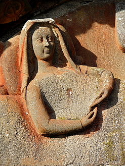 The Virgin Mary in the nativity scene. She lies on a bed with arms across her chest. Most of her body has been chiseled away it is thought by a rector of the church who thought the depiction of her body to be indiscreet.