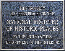 A black-and-bronze plaque reading "This Property Has Been Placed on the National Register of Historic Places by the United States Department of the Interior".