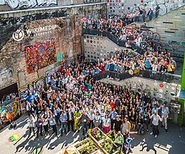 Wikimedia Conference 2018 group photo, at rail with blue shirt in middle of right third