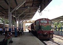 Maroon diesel-powered passenger train pulling into a station