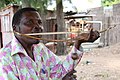 Mozambique, 21st century. Man playing a heterochord musical bow, using his mouth for a resonator.